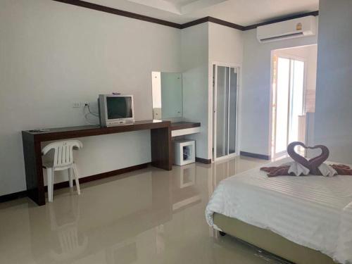 a bedroom with a bed and a desk with a television at Tan Residence in Ko Lanta