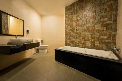 a bathroom with a tub and a toilet and a sink at AB Inn Hotel in Kulai