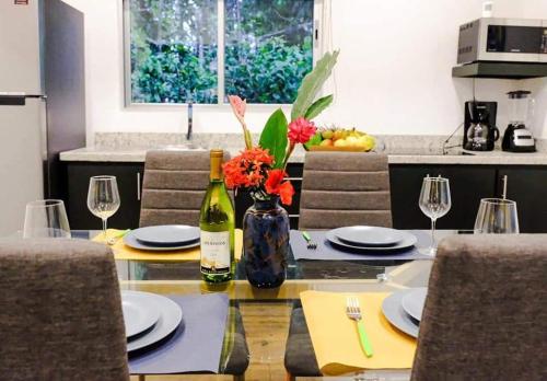 a dining table with a bottle of wine and flowers on it at Alloro Jungle Villas in Puerto Viejo