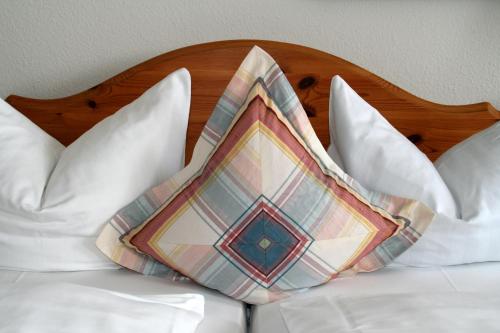 a pillow sitting on top of a bed with white pillows at Posthotel Kolberbräu in Bad Tölz