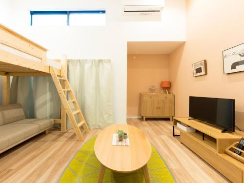 a living room with a couch a table and a tv at TRIP POD TAKASAGO B in Fukuoka