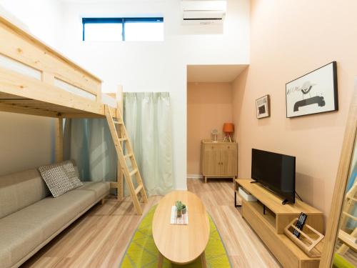 a living room with a couch and a tv and a bunk bed at TRIP POD TAKASAGO B in Fukuoka