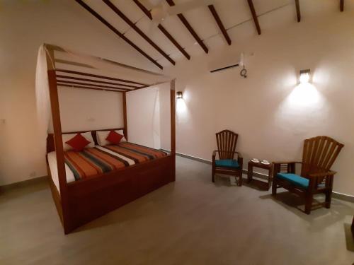 a bedroom with a bed and two chairs and a table at Jackland Holiday Cabanas in Demanhandiya