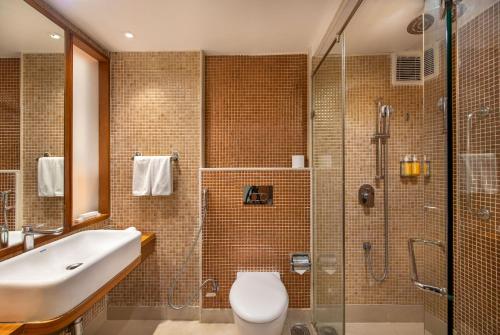a bathroom with a shower and a toilet and a sink at BloomSuites l Ahmedabad in Ahmedabad