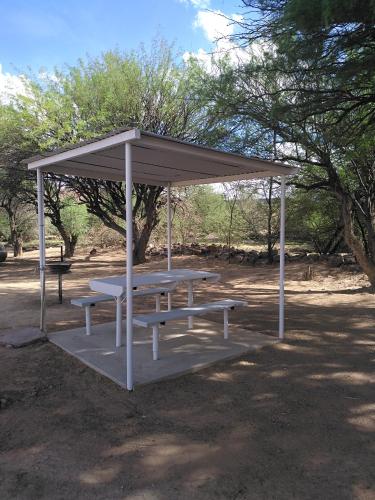 a picnic shelter with a picnic table in a park at Old Bridge Camping in Maltahöhe