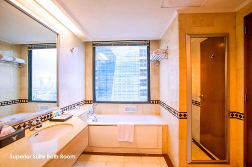 a bathroom with a tub and a sink and a window at Menara Peninsula Hotel in Jakarta