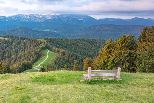 a bench sitting on top of a hill overlooking a valley at Posthotel Kolberbräu in Bad Tölz