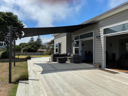 a patio with couches on a house at Otaki Beachfront Getaway in Otaki Beach