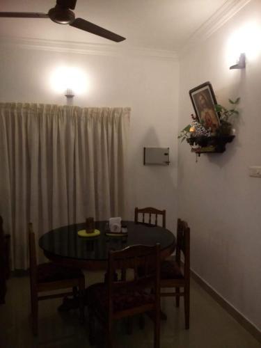 a dining room with a table and chairs and a ceiling fan at Nathans Holiday Home in Cochin