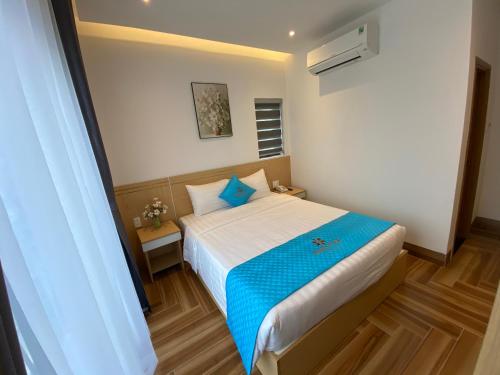 a bedroom with a bed with a blue blanket at Euro Star Riverside Hotel in Da Nang