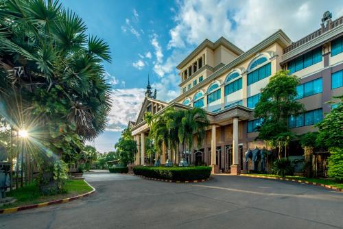 a large building with palm trees in front of it at Pacific Hotel & Spa in Siem Reap