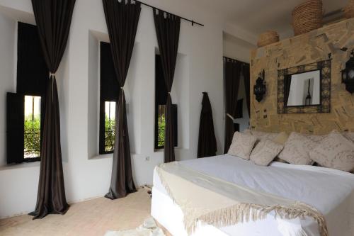 a bedroom with a white bed and some windows at Fawakay Villas in Sfiani