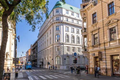 ein hohes weißes Gebäude mit einem grünen Dach auf einer Stadtstraße in der Unterkunft Hotel Capital in Zagreb