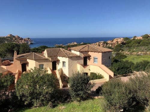 ein Haus auf einem Hügel mit dem Ozean im Hintergrund in der Unterkunft Appartamenti Costa Rossa Cala Rossa in Isola Rossa