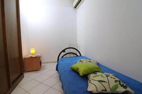 a bedroom with a blue bed with two green pillows at Casa vacanze Clio in Salento in Otranto