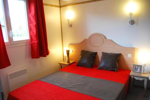 a bedroom with a red bed with two pillows at Lagrange Grand Bleu Vacances – Résidence Port Lalande in Castelmoron-sur-Lot