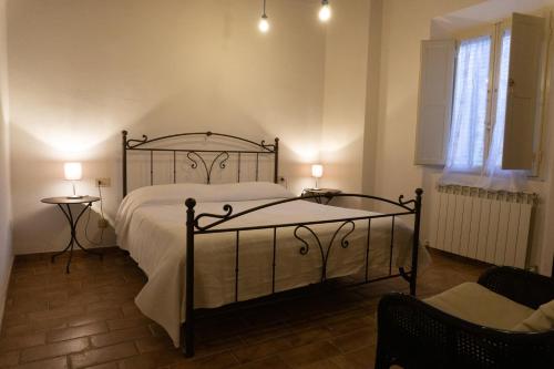 ein Schlafzimmer mit einem Bett, zwei Tischen und einem Fenster in der Unterkunft Pancotto - Appartamento nel cuore di San Gimignano in San Gimignano