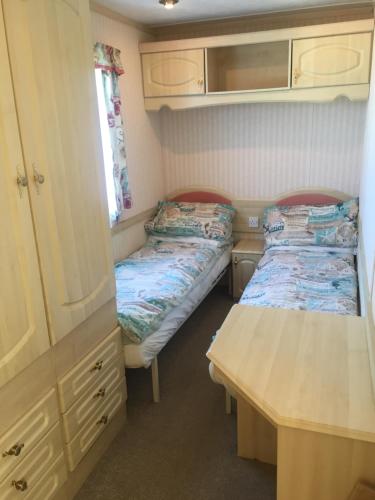 a small room with two beds and a desk at Three bedroom Hartland Caravan in Bideford