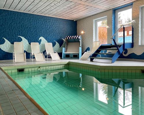 uma piscina com cadeiras brancas e uma piscina em WAGNERS Hotel Schönblick, C&C Hotels und Vertrieb GmbH em Fichtelberg