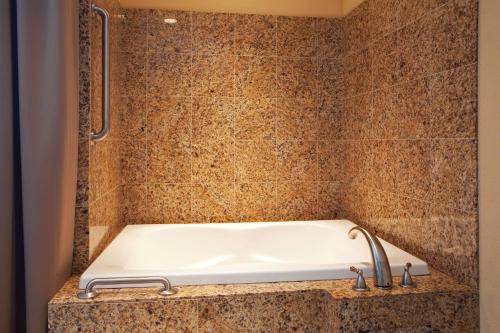 a bath tub in a tiled bathroom with a sink at Holiday Inn Houma, an IHG Hotel in Houma