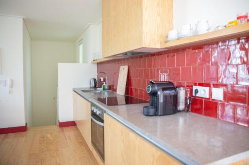 a kitchen with a counter and a red tile wall at Casa René - Charming apartments in Almada