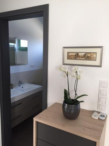 a bathroom with a sink and a vase with flowers on a counter at Jókai Apartman in Dunaföldvár