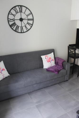 a gray couch with a clock on a wall at Duque de Loulé - Apartments - Apartamento G in São Martinho do Porto