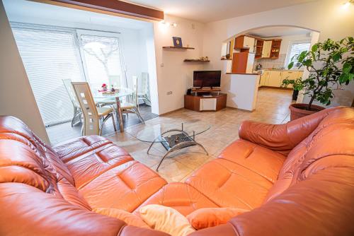 a living room with a leather couch and a kitchen at Apartments Ole in Tolmin