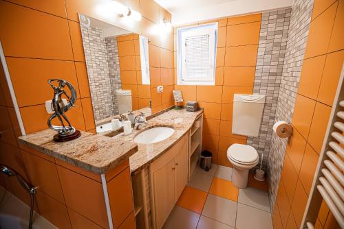 an orange bathroom with a sink and a toilet at Apartments Ole in Tolmin