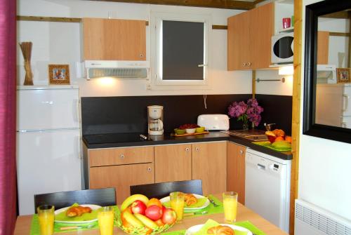 a kitchen with a table with a plate of fruit on it at Lagrange Grand Bleu Vacances – Résidence Port Lalande in Castelmoron-sur-Lot