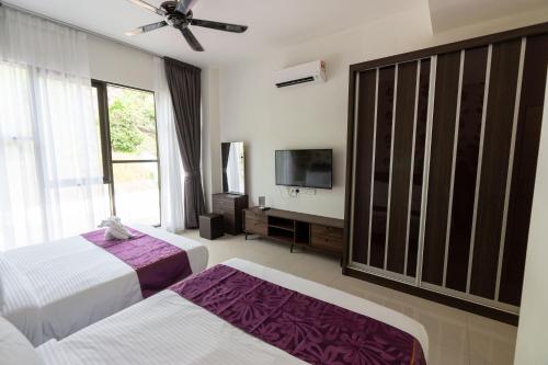 a bedroom with two beds and a flat screen tv at Rock Mountain in Raub