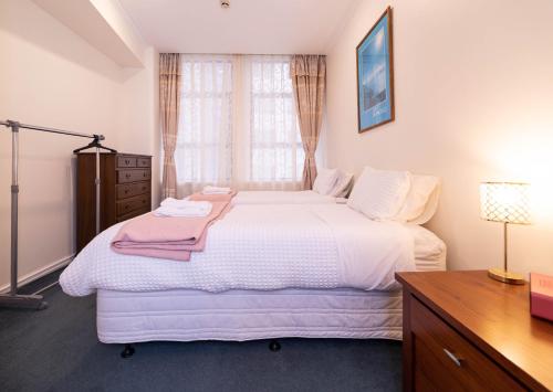 a bedroom with a large white bed and a window at Wellington CBD Apartment in Wellington