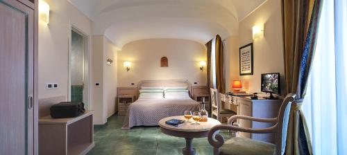 una camera con letto e tavolo con bicchieri di vino di Hotel Royal Terme a Ischia