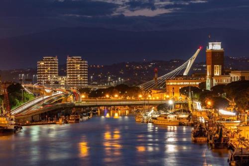 a city at night with a bridge and boats in the water at La casa di Alvy in Pescara