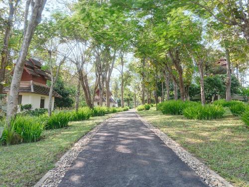 a tree lined road with a house in the distance at MonPanaNont Wellness Resort & Spa in Mae Taeng