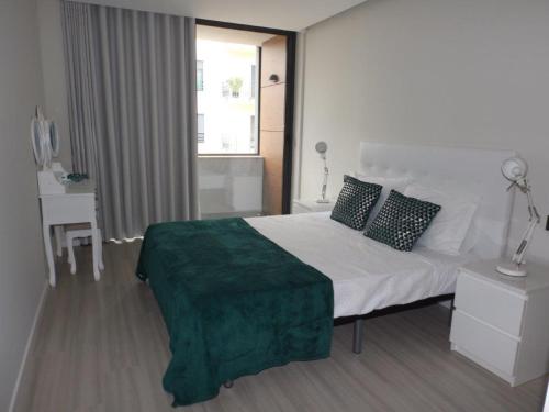 a bedroom with a bed with a green blanket on it at Duque de Loulé - Apartments - Apartamento E in São Martinho do Porto