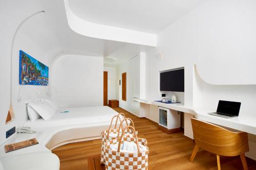 a white room with a bed and a desk with a laptop at Approdo Resort Thalasso Spa in Castellabate