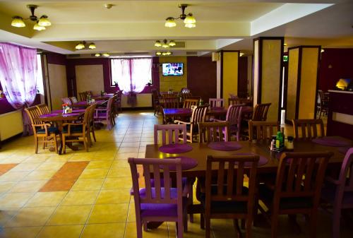 a dining room with tables and chairs and a tv at Pensiunea Bucura in Călimăneşti