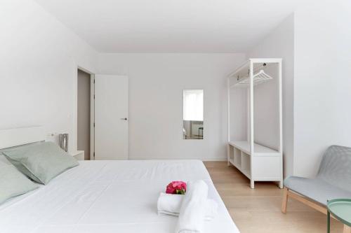 a white bedroom with a large bed and a chair at Piso recién reformado en el centro de Pamplona in Pamplona