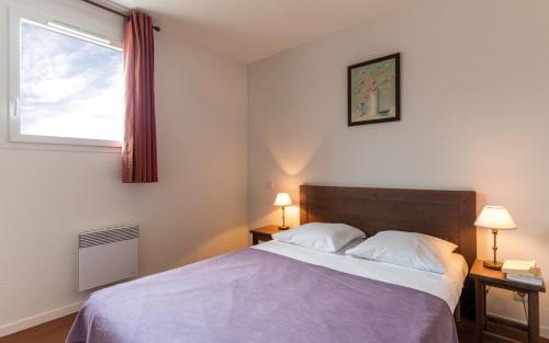 een slaapkamer met een bed met 2 lampen en een raam bij Le Domaine des Cazelles by Ateya Vacances in Cajarc