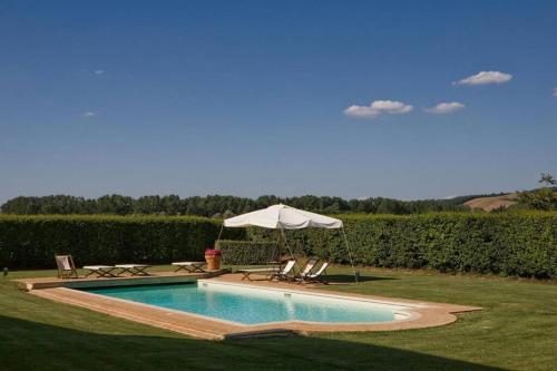 a swimming pool with an umbrella and chairs at Villa Ponte in Ponte dʼArbia