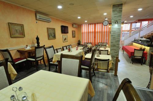 a dining room with tables and chairs and a clock at Motel Edem in Mostar