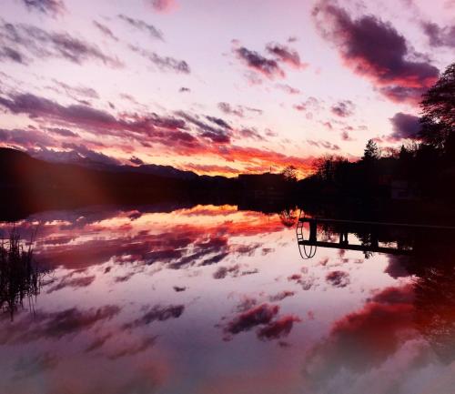 a reflection of a sunset in a lake at Haus Luca Seeblick in Pörtschach am Wörthersee