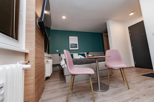 a small room with a table and two pink chairs at Apartments 4u: KAMPUS Hradec Králové in Hradec Králové