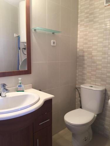 a bathroom with a toilet and a sink and a mirror at Atic in L'Ampolla