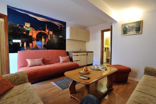 موتيل إيديم في موستار: غرفة معيشة مع أريكة حمراء وطاولة