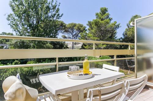 a white table on a balcony with a bottle of wine at Résidence Pierre & Vacances La Corniche d'or in Boulouris-sur-Mer