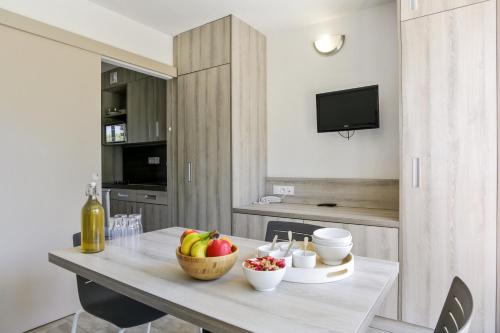 - une cuisine avec une table et un bol de fruits dans l'établissement Résidence Pierre & Vacances La Corniche d'or, à Boulouris-sur-Mer
