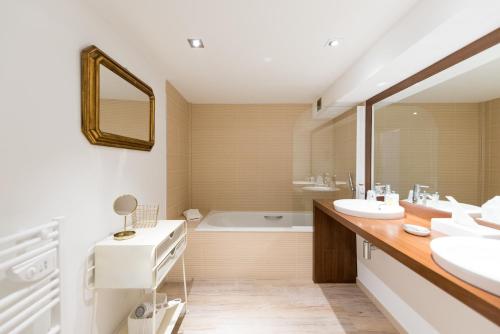 La salle de bains est pourvue de 2 lavabos et d'une baignoire. dans l'établissement Hôtel La Jetée, à Saint-Martin-de-Ré
