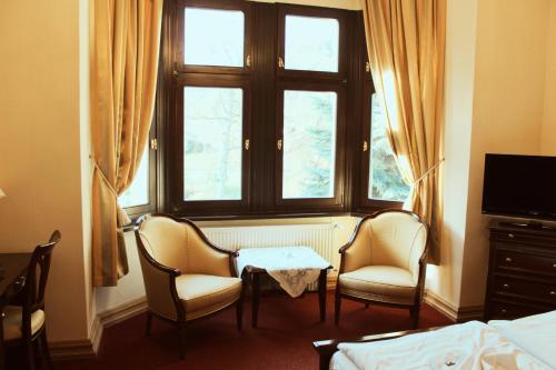 a bedroom with two chairs and a table and a window at Schlosshotel Stecklenberg in Thale